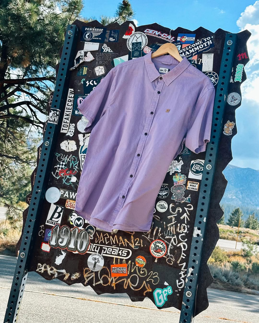 Kaya Unite — camisa lila sobre panel gráfico